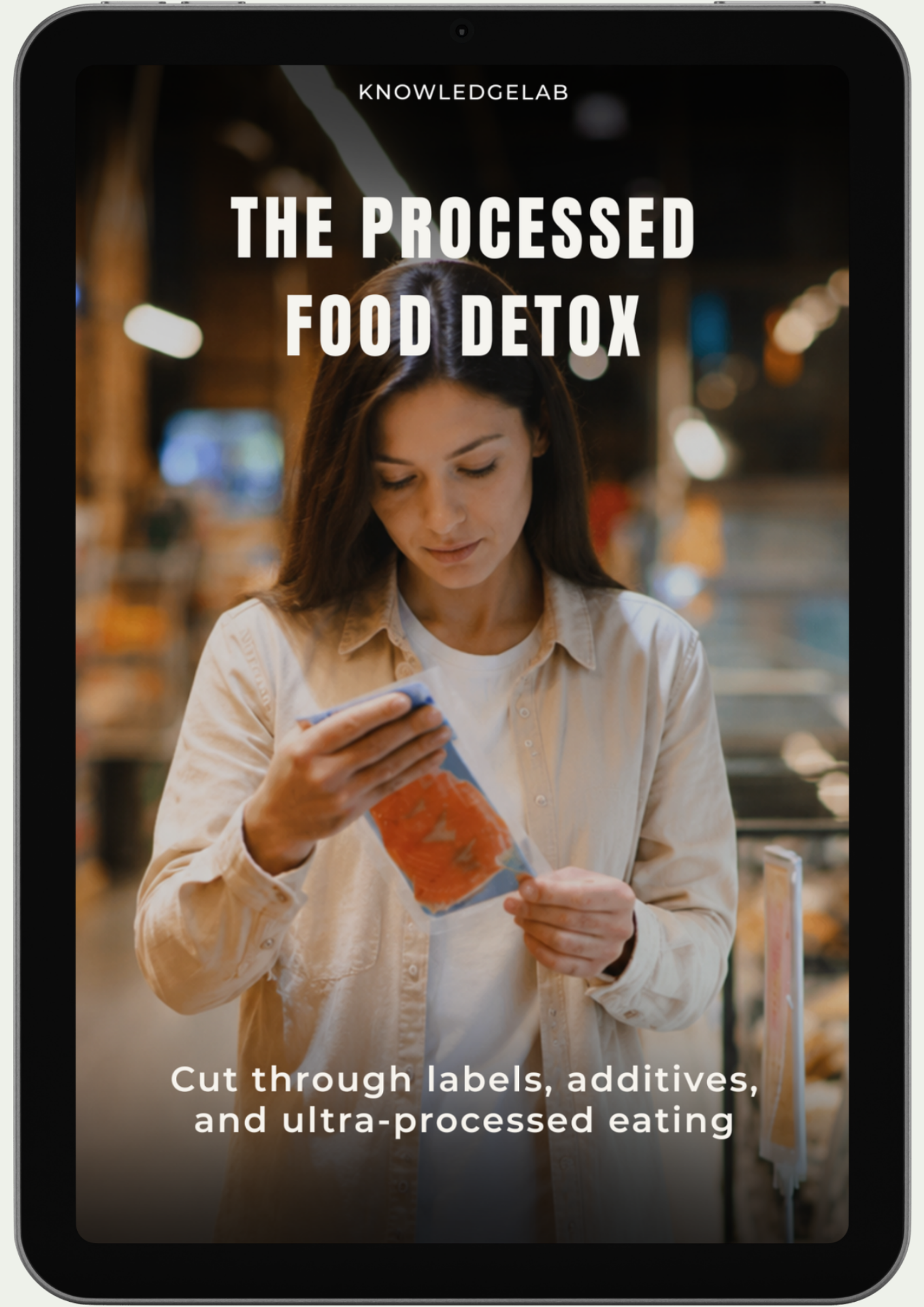 A woman stands in a grocery store reading a food label. Text: The Processed Food Detox—cut through labels, additives, and ultra-processed foods for a cleaner, healthier way of eating.