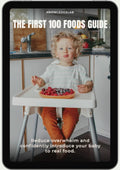A young child eats fruit from a plate while sitting in a high chair. The image is titled "The First 100 Foods Guide" and features text about reducing overwhelm with a baby food tracker to confidently introduce real foods.